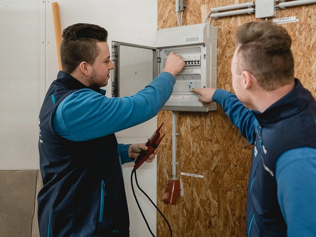 Zwei Männer in einem Raum, die an einem Panel für Elektroarbeiten arbeiten