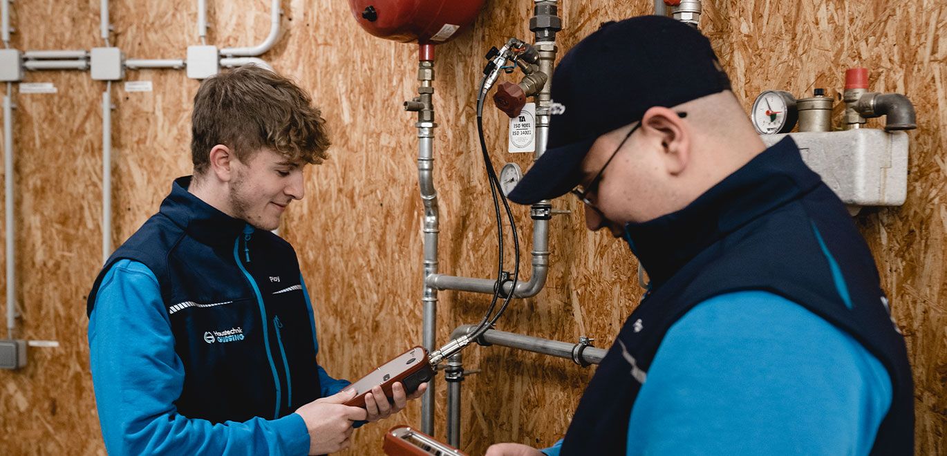 Zwei Mitarbeiter in blauen Jacken betrachten ein Gerät